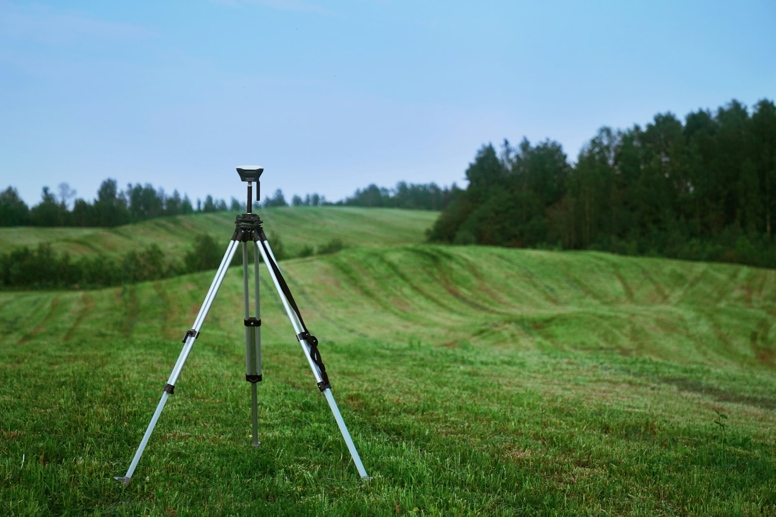 Surveyor total station on a tripod in an open field, used to produce a registered plano catastrado