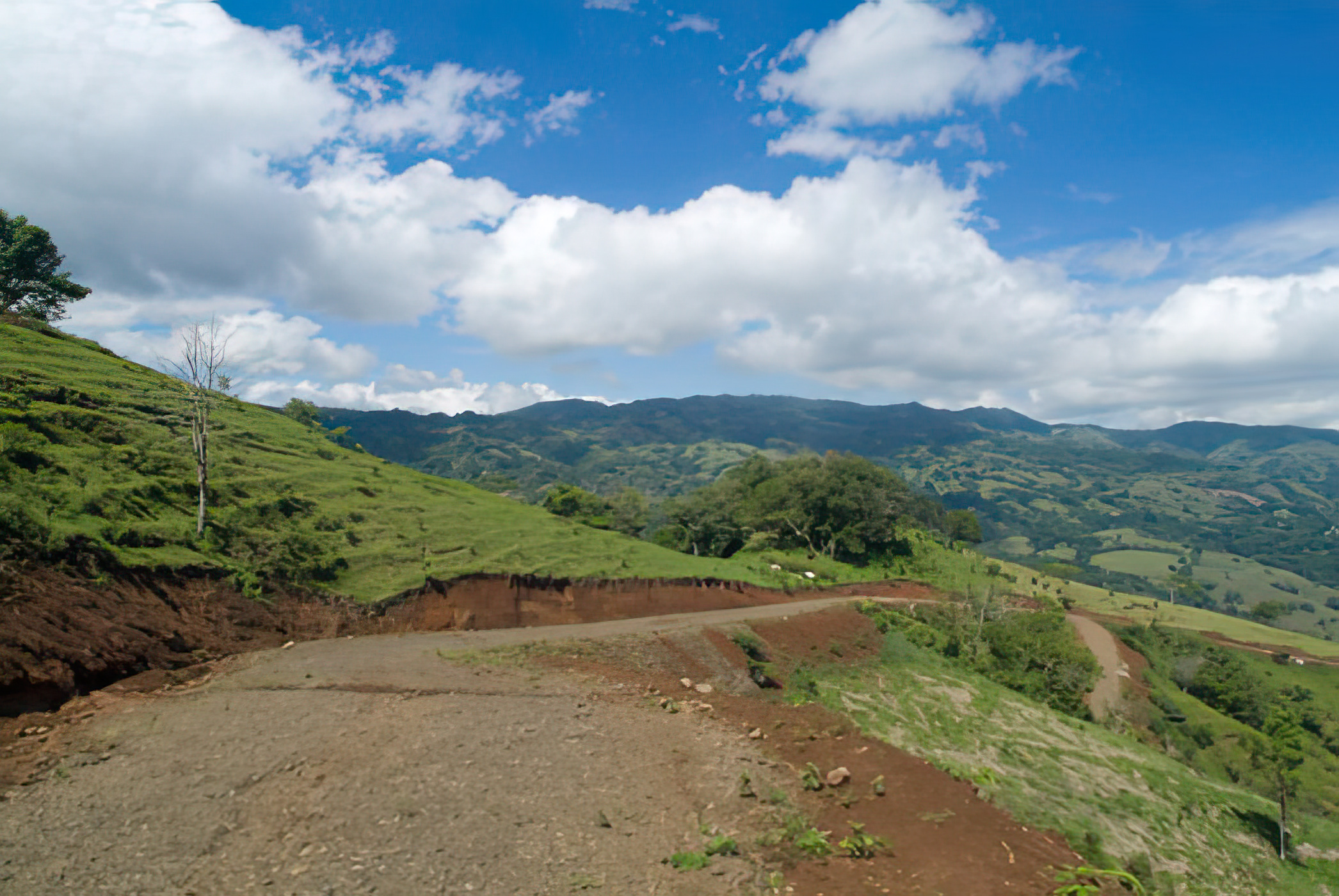 Freshly graded gravel road bench in red earth on a Puriscal hillside