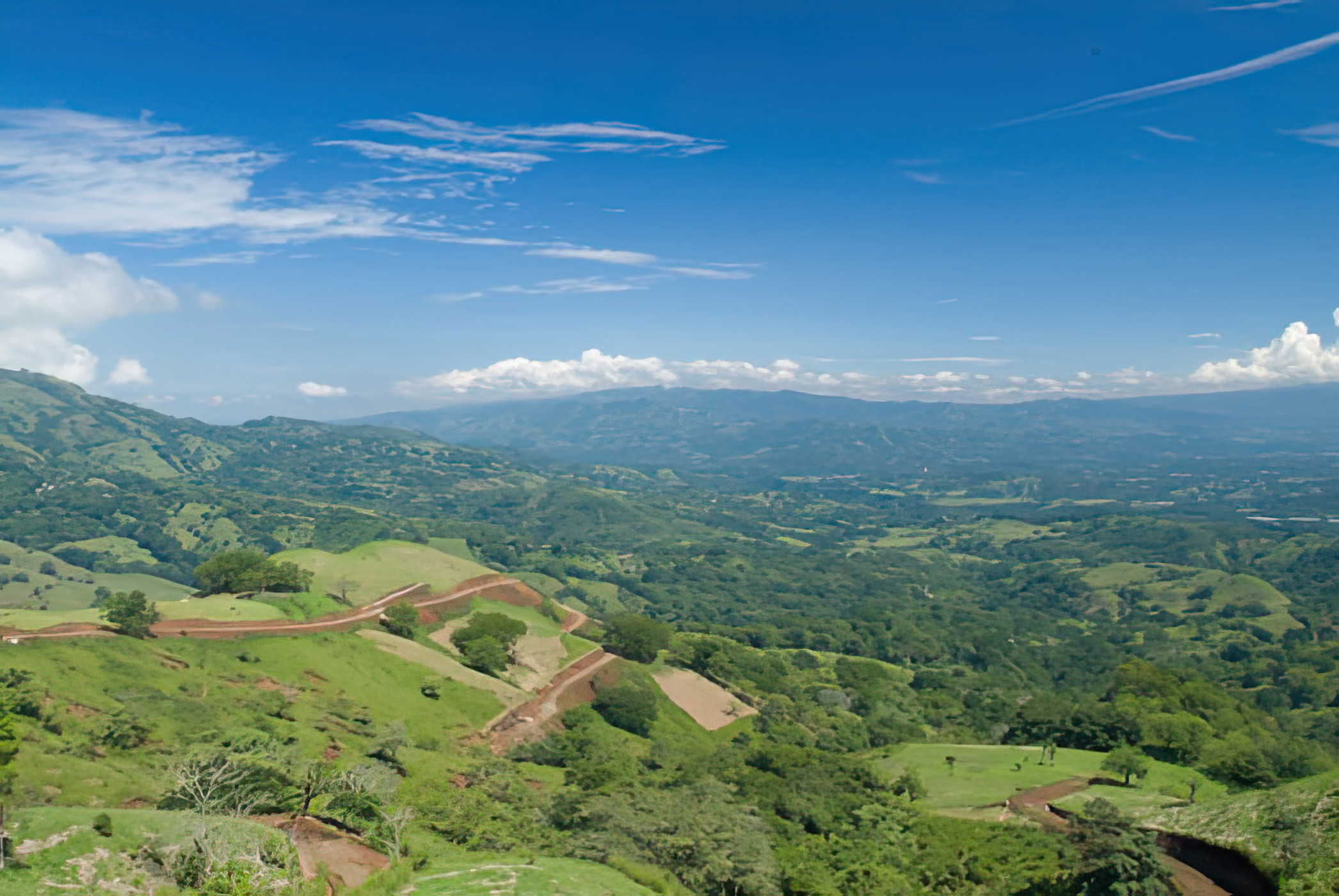 Graded access road switchbacking down a hillside above the Central Valley in Puriscal